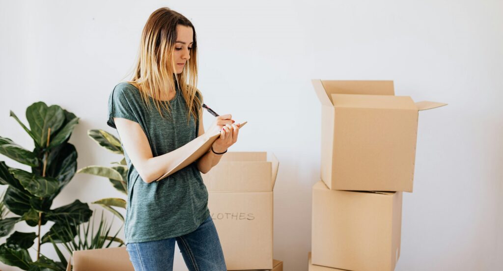 woman writing a list with cardboard boxes in the background