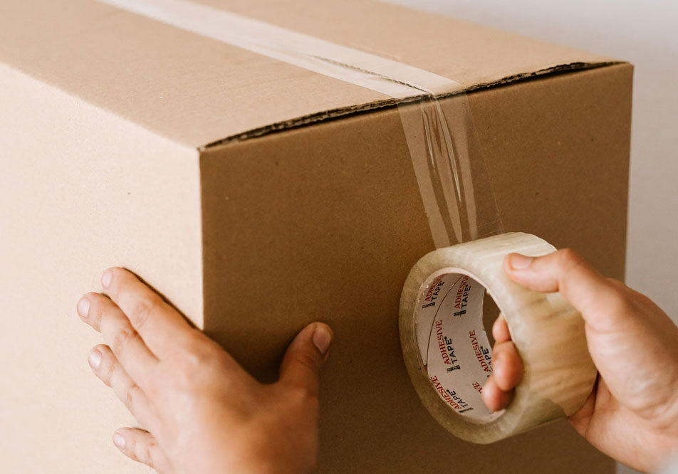 A cardboard box being sealed with packing tape